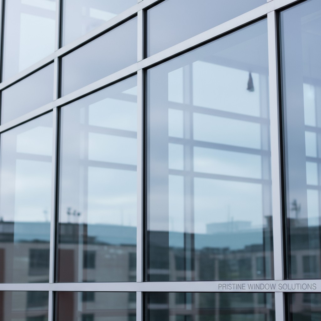 A glass building with a cityscape reflected in its windows.